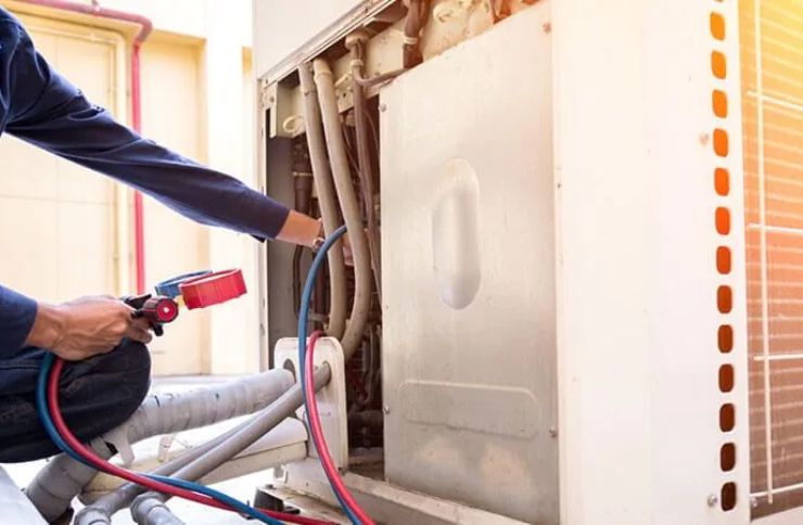A man services an air conditioner, highlighting a heating and air conditioning repair service in Henderson, NV.