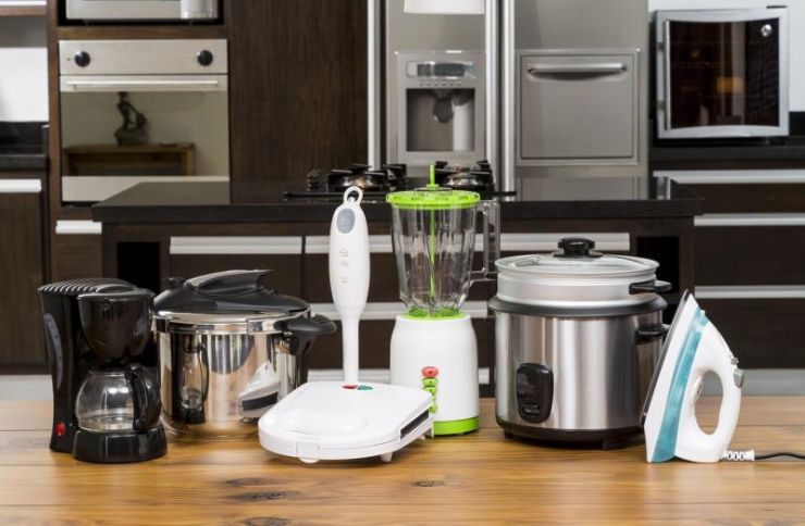 . A cluttered kitchen table displaying multiple small appliances, highlighting a repair service based in Henderson, NV.