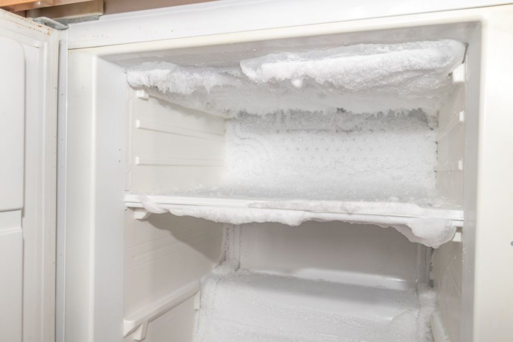 An open refrigerator showcasing shelves covered in ice, highlighting a cold and frosty interior.