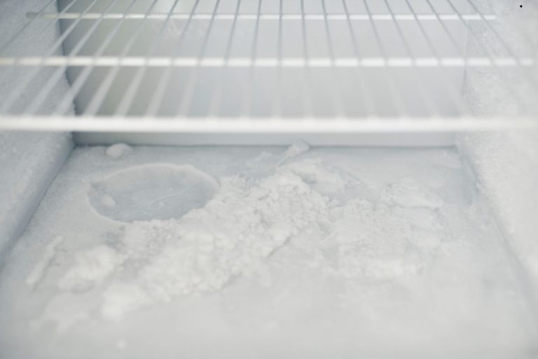A white refrigerator filled with ice, emitting an unpleasant odor.