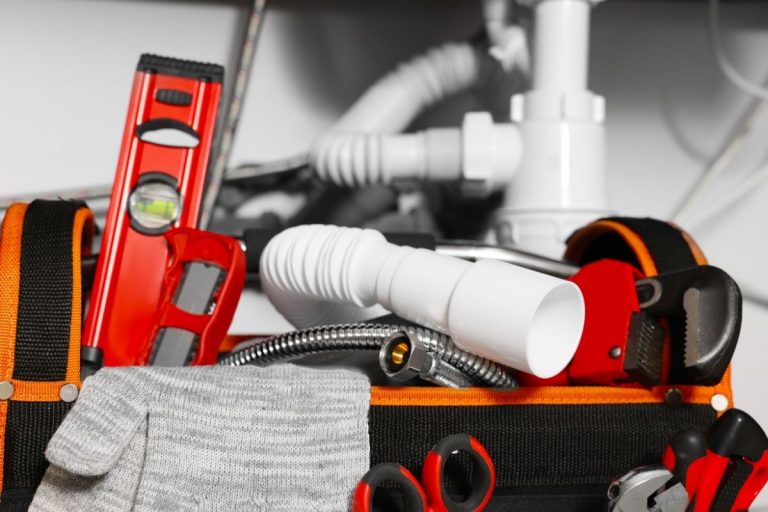 A tool bag filled with various plumbing supplies, including wrenches, pipes, and fittings, organized for easy access.